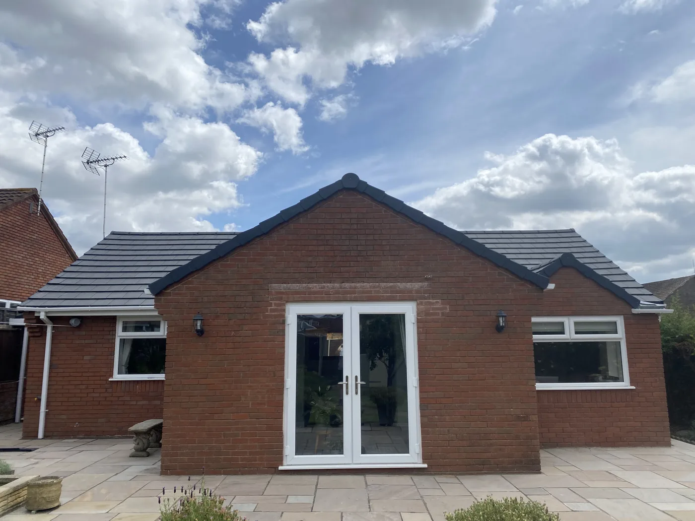 Bungalow with a completed new roof in dark grey flat tiles, new white fascias and guttering