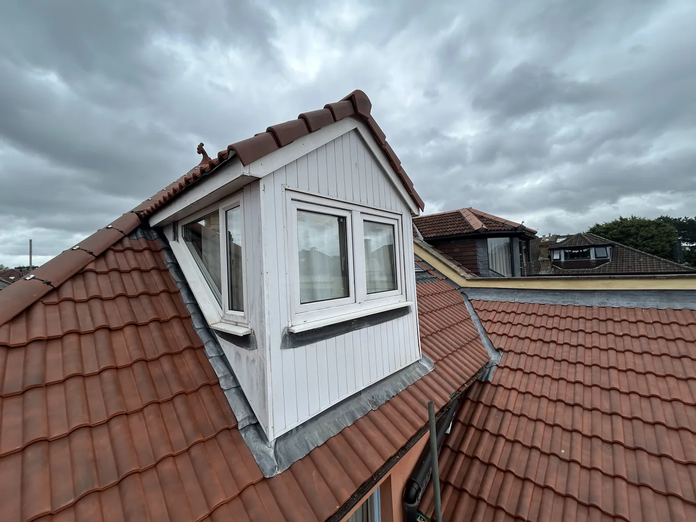 Dormer window with newly laid red pantiles around it and fresh lead flashing dressed into the cheeks