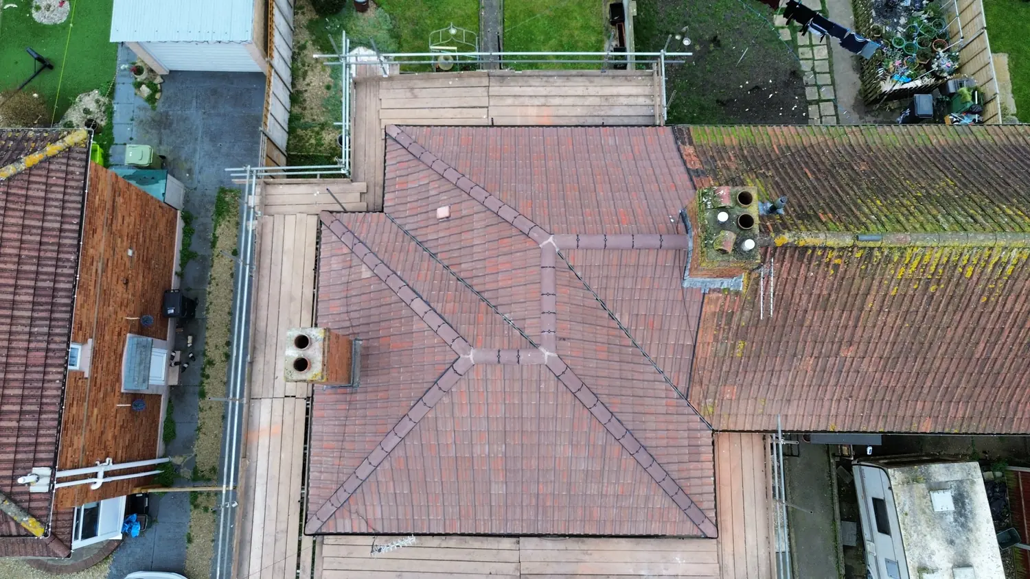 Overhead drone view of a completed hipped roof re-tiled in red, with the ridge and hips run straight