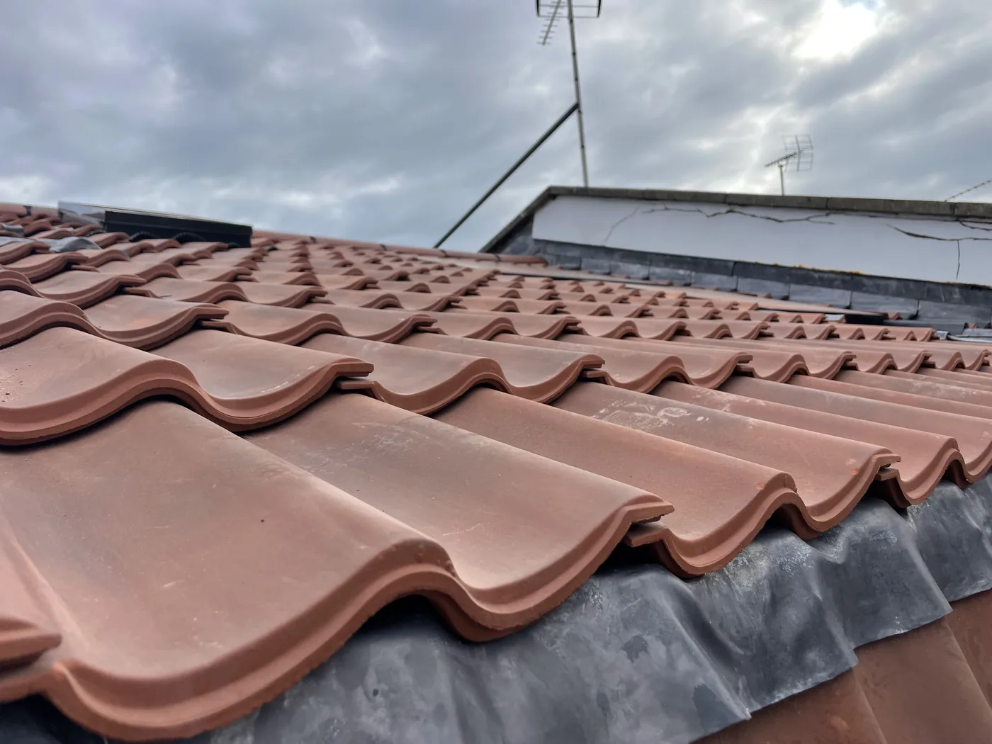 Close-up of newly laid interlocking pantiles meeting a lead-lined valley